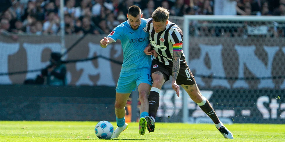 Matus Bero vom VfL Bochum im hellblauen Trikot und Eric Smith vom FC St. Pauli üben gemeinsam für den dreibeinigen Wettlauf. (Foto)