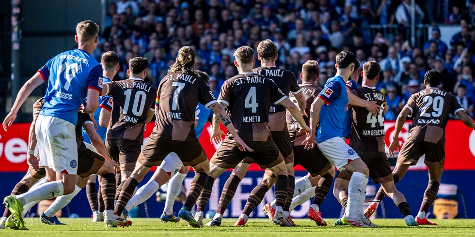 Spielszene mit dichtem Gedränge im Strafraum: Mehrere Spieler des FC St. Pauli in braunen Trikots stehen Holstein-Kiel-Spielern im blauen Trikot gegenüber. (Foto)