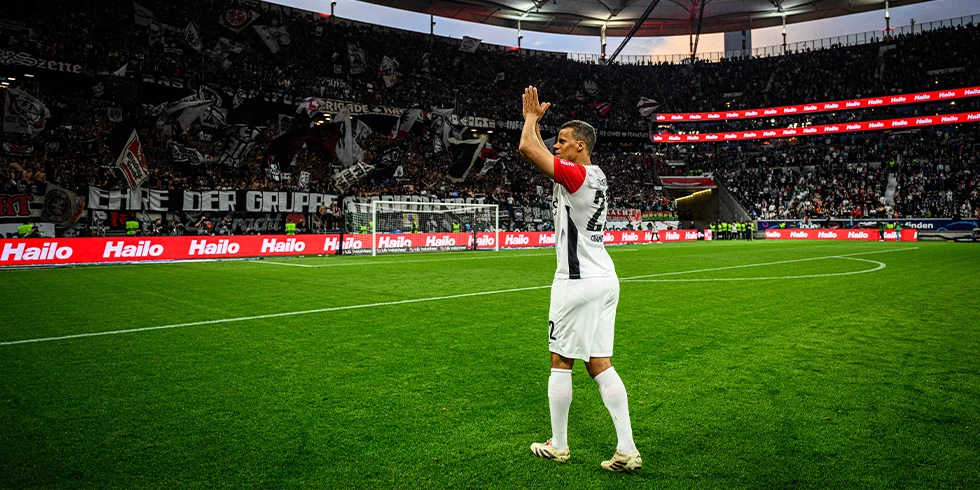 Aurélio Buta von Eintracht Frankfurt klatscht nach dem Spiel den Fans im Stadion zu, während die Kurve voller Fahnen jubelt. (Foto)
