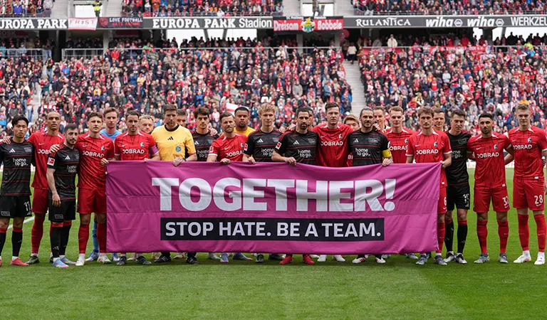 Die Mannschaften vom 1. FC Union Berlin und dem SC Freiburg halten gemeinsam ein Banner mit der Aufschrift: "TOGETHER! STOP HATE. BE A TEAM." hoch. (Foto)