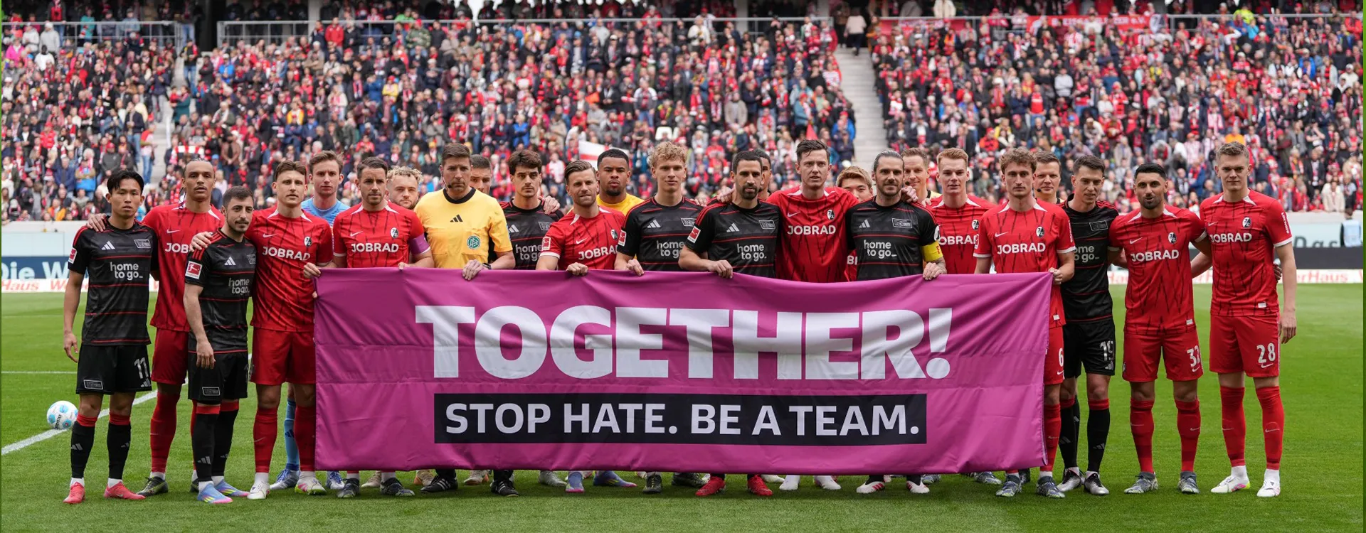 Die Mannschaften vom 1. FC Union Berlin und dem SC Freiburg halten gemeinsam ein Banner mit der Aufschrift: "TOGETHER! STOP HATE. BE A TEAM." hoch. (Foto)