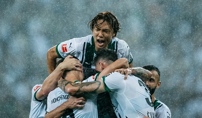 Ko Itakura von Borussia Mönchengladbach stützt sich auf jubelnde Mitspieler. (Foto)
