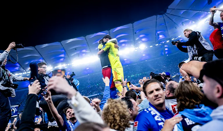 Der Torwart des HSV und ein weiterer Spieler umarmen sich nach dem Aufstieg auf dem Platz. (Foto)
