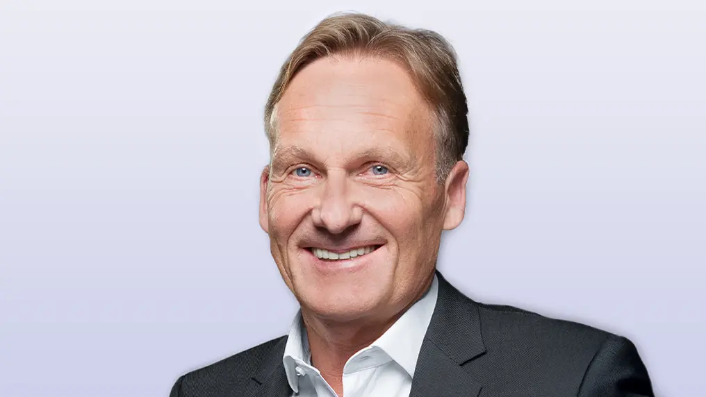 Ein älterer, blonder Herr in einem dunkelgrauen Anzug lächelt in die Kamera. (Foto)