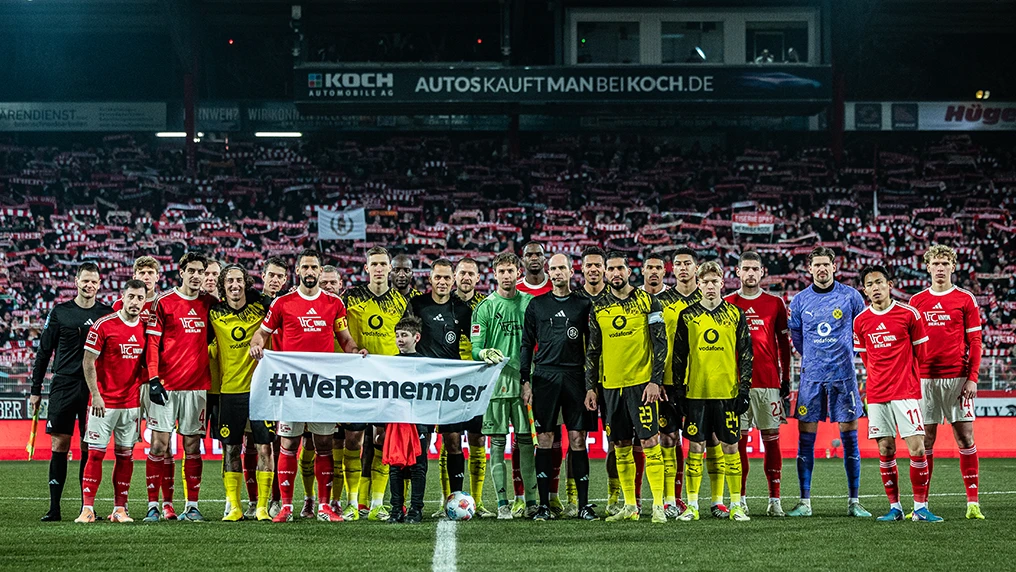 Spieler von Borussia Dortmund und 1. FC Union Berlin halten am 22. Erinnerungstag einen Banner mit der Aufschrift "#WeRemember" hoch (Foto)