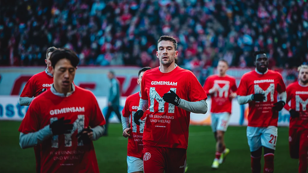 Spieler des 1. FSV Mainz 05 wärmen mit Shirts auf, die auf den Aktionstag "Gemeinsam für Erinnerung und Vielfalt" hinweisen (Foto)