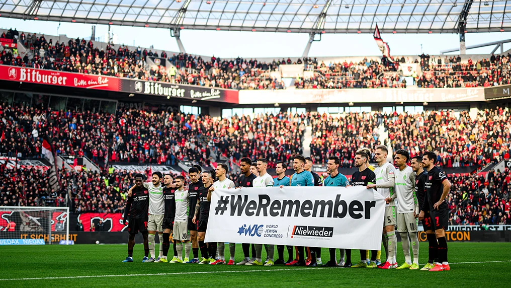 Spieler von Bayer 04 Leverkusen und SV Werder Bremen halten am 22. Erinnerungstag einen Banner mit der Aufschrift "#WeRemember" hoch (Foto)