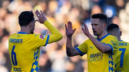Zwei Spieler von Eintracht Braunschweig sind im Begriff, sich abzuklatschen. (Foto)