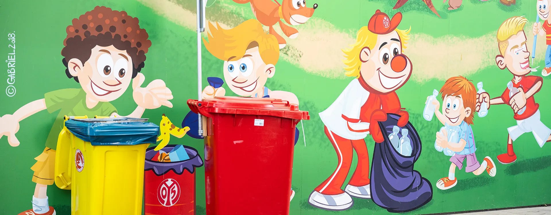 At the FSV Mainz 05 stadium, a yellow and a red rubbish bin stand in front of a painted wall depicting a clean-up operation in the forest. (Photo)