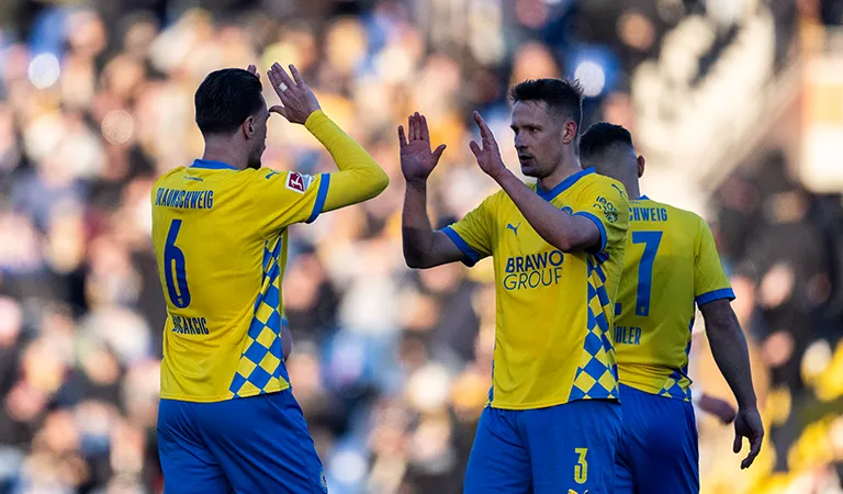Two players from Eintracht Braunschweig are about to high-five each other. (Photo)
