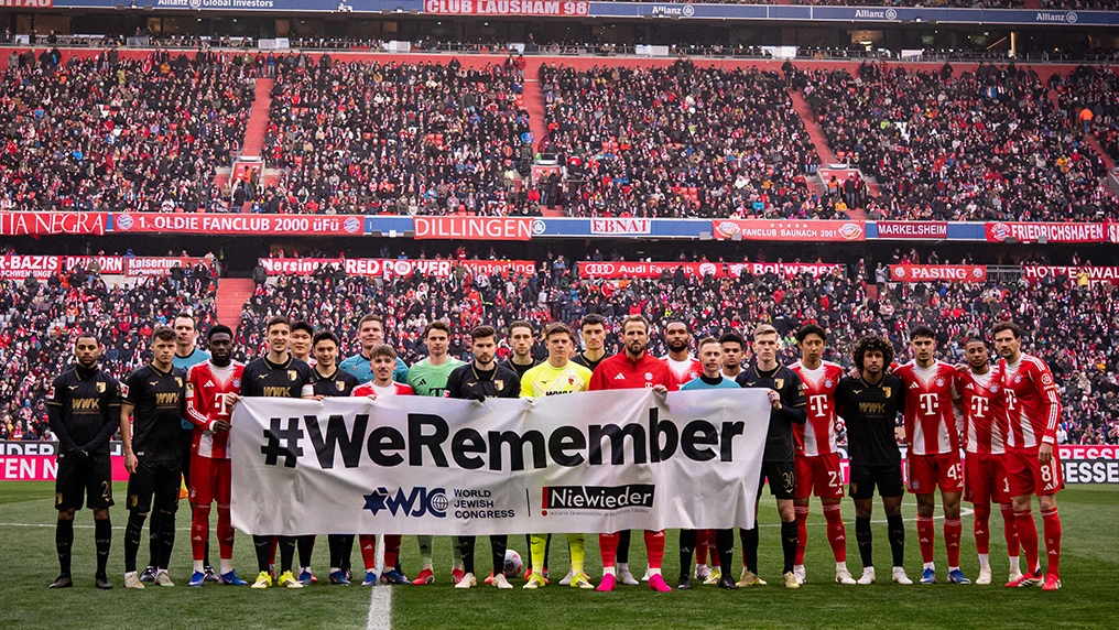Players from FC Bayern Munich and FC Augsburg hold up a banner reading “#WeRemember” on the 21st day of remembrance. (Photo)