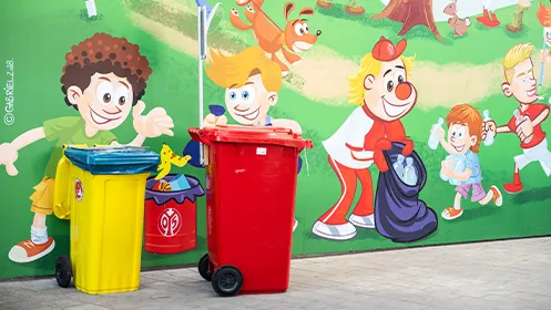 At the FSV Mainz 05 stadium, a yellow and a red rubbish bin stand in front of a painted wall depicting a clean-up operation in the forest. (Photo)